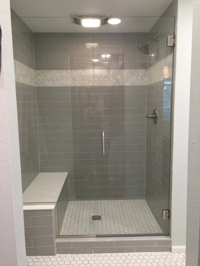 The large walk in shower with oversized subway tile and a herringbone band.