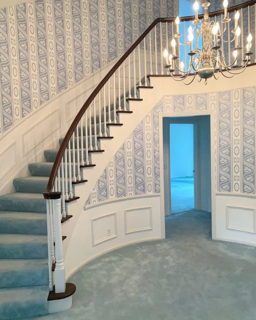 The beautiful foyer of our new home with the blue carpet and wallpaper.