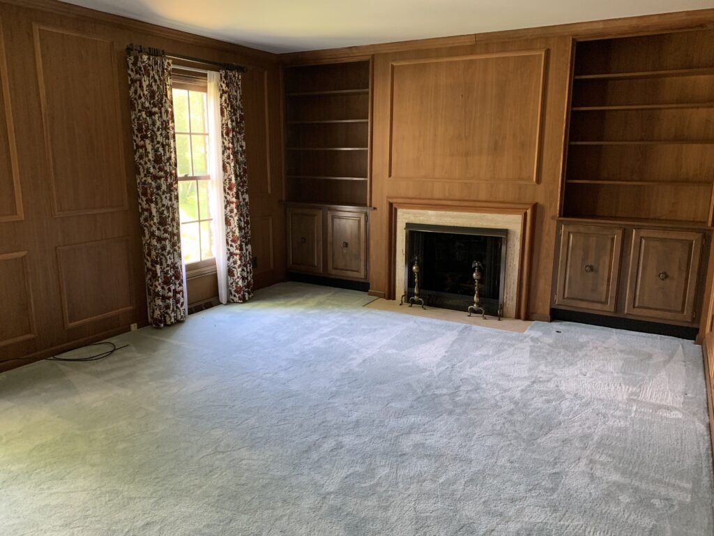 The formal office in our new home with wood paneling, a fireplace and built in bookcases.